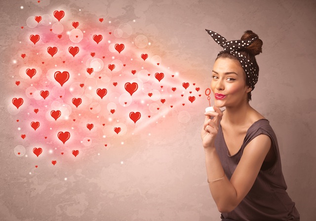 Pretty young girl blowing red heart symbols