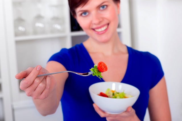 young woman offering a healthy green salad